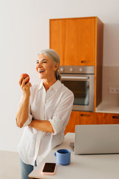 Woman laughing enjoying healthy snack at home kitchen