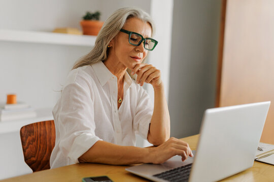 Mature woman wearing glasses working on laptop