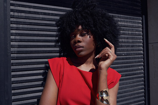 Woman in red dress poses against black wall