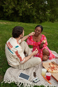 Couple enjoys food together on a picnic blanket