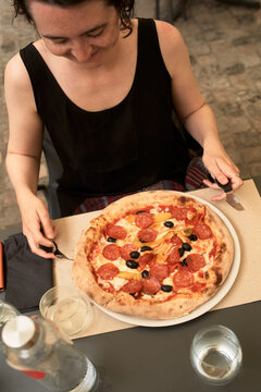 Woman Enjoys a Pizza at a Table Outside in a City Setting