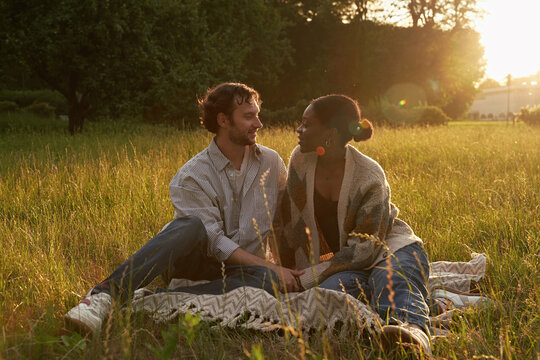 Couple sits on blanket in green field during sunset