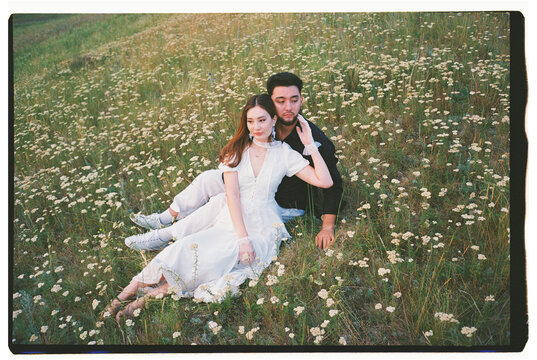 Young Couple Relaxing Together in a Wildflower Meadow at Sunset