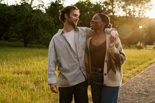 Couple enjoys walk in park during golden hour light