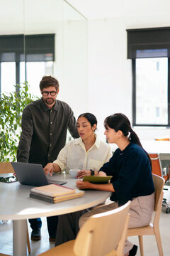 Team Reviewing Project On Laptop During Office Meeting