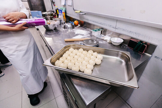 Cook covering tray of dumplings
