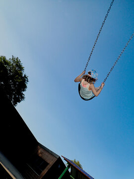 Child Swinging High in Against Blue Evening Sky