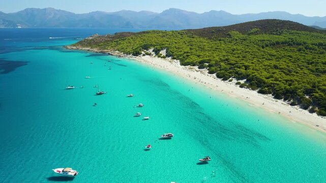 Saleccia Beach Corsica France aerial drone flyover turquoise sea yachts rocky cove emerald water boats mountains landscape Agriates desert travel destination 4k video