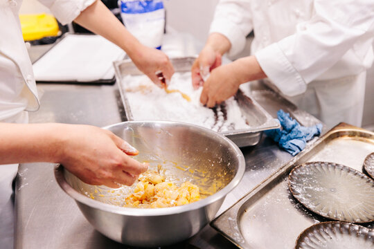 Chefs coating ingredients in flour