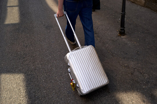 Person Pulling a Suitcase on the Street in a Busy Area
