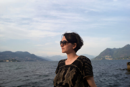 Woman Stands by the Shoreline Looking out at the Water and Hills
