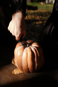Close up of anonymous female hand stabbing a pumpkin at Halloween