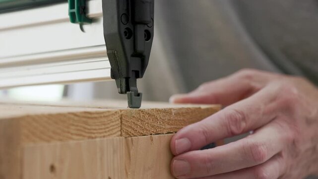woodworker using a power nailer on a wooden box
