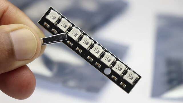 Led strip with hard mount pcb surface and argb leds held by tweezers close-up macro shot