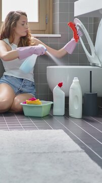 Exhausted young woman Spraying Disinfectant and Wiping Toilet Seat