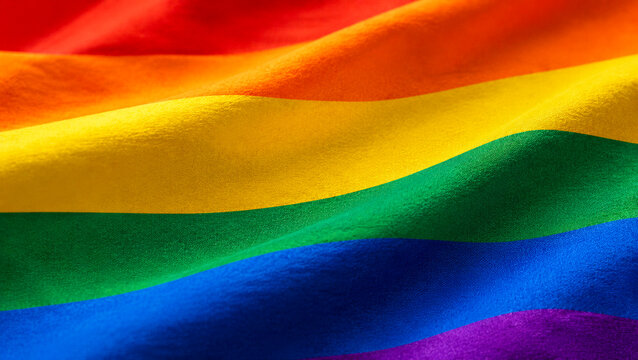 Close-up of a rainbow pride flag with flowing fabric folds and vivid color stripes
