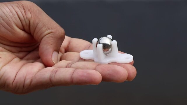 caster wheel for robotic car with shiny metal ball and plastic frame held in the hand