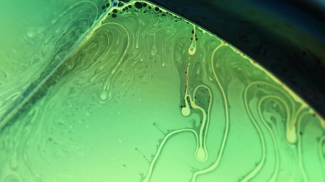 Emerald green liquid film facet with intricate convection tendrils and dark rim border. A low-key macro photograph capturing a liquid film plane glowing in bright emerald green backlight
