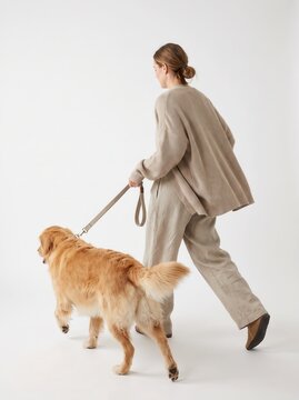 Rear view of a woman in gray casual loungewear walking her fluffy dog on a leash, isolated on white background.-1