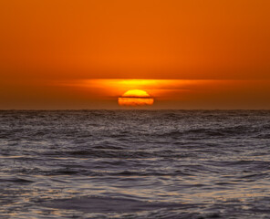 Fototapeta premium Deep Orange Sun Sinks Into The Clouds And Pacific Ocean