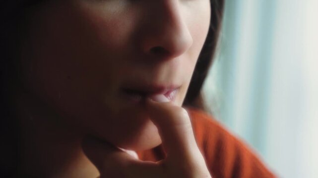 Close-up of an anonymous woman biting her nails in anxiety, conveying nervousness, stress, worry, and emotional tension in a candid lifestyle moment.
