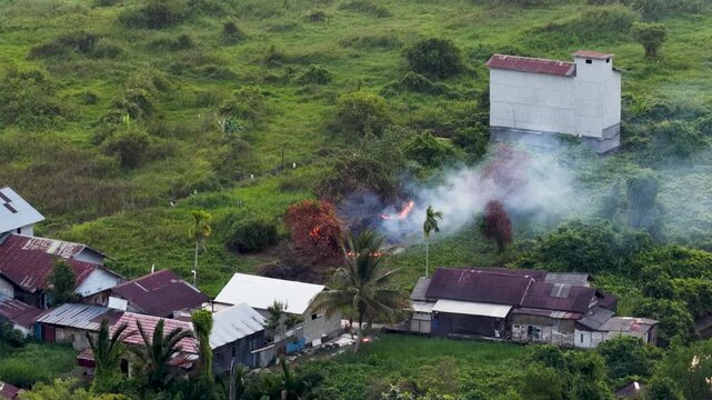 Smoke rises from a small vegetation fire near rural houses and a swiftlet building in Kalimantan