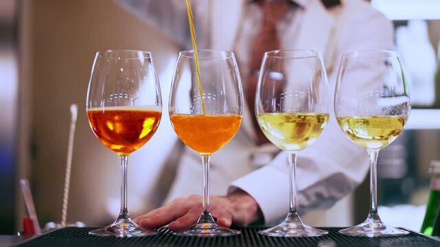 Talented barkeeper pouring Aperol Spritz mixing it with refreshing Prosecco in glass, preparation of cocktails at the bar counter, aperitif and entertainment