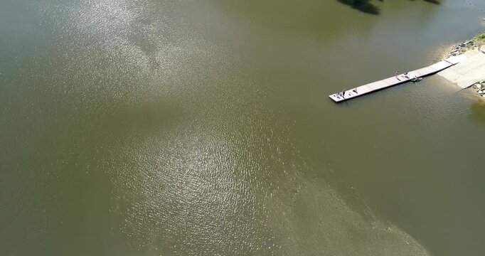 Drone shot captures tranquil river surface and wooden dock