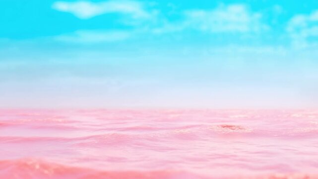 Pastel pink ocean waves ripple gently beneath bright cyan sky, forming a low open horizon with soft white clouds, shimmering highlights, and calm expansive water stretching into distance