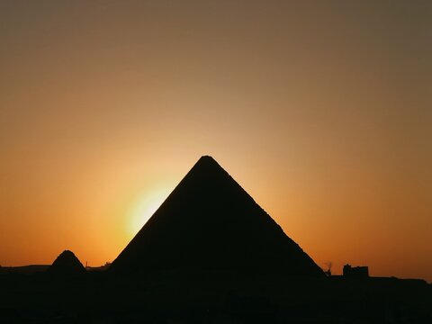 Pyramid silhouette at sunset with glowing sun