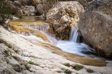 A beautiful small waterfall cascades smoothly over rocks through a narrow rocky canyon. © @CMG_IG
