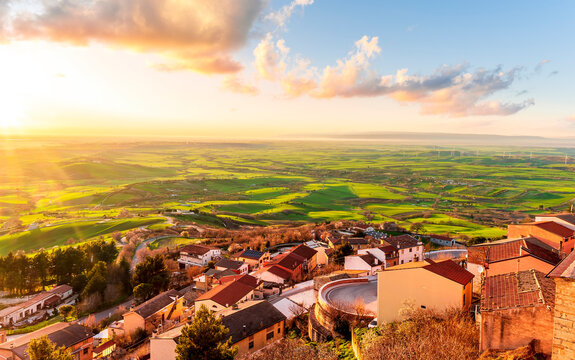 scenic evening sunset landscape with beautiful view og vintage town with traditional roofs and houses and green and golden walley hills with farmland and cloudy sky