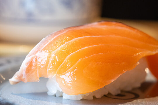 Close-up macro shot of salmon belly nigiri sushi with detailed natural pattern on the skin.