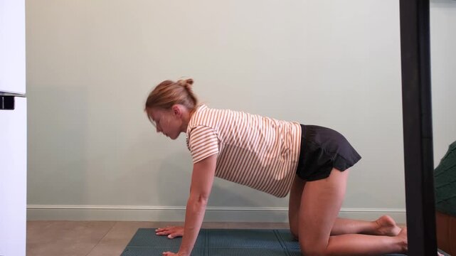 Mourning routines. middle adult woman training at small apartment in narrow corridor sitting on training mat