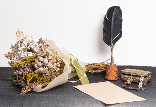ramo de flores secas con un cofrecillo joyero, pluma antigua de escritura y un papel en blanco