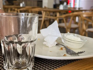 Fotobehang Horeca Empty water glass and finished plate with napkin at restaurant table  © Vertstyle