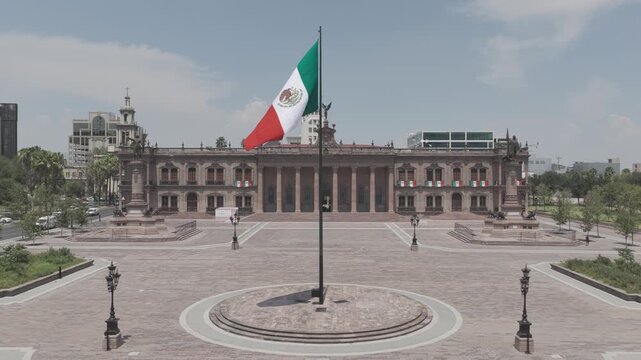 Aerial hovering shot of the Mexican flag waving over the Explanada de los H&eacute;roes and the Palacio de Gobierno in Monterrey, Nuevo Le&oacute;n. D-Log M