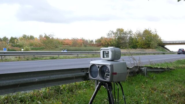 Mobile speed camera radar on a tripod monitoring traffic on a dual carriageway in autumn, road safety enforcement in France