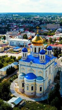 Vertical video. Yelets, Lipetsk region, Russia. Ascension Cathedral, white stone walls and gilded dome rising above blue rooftops, Drone footage over the historic city center. Drone footage, Departur