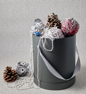 A cardboard box with Christmas tree decorations, pine cones, and ornaments for New Year's decor