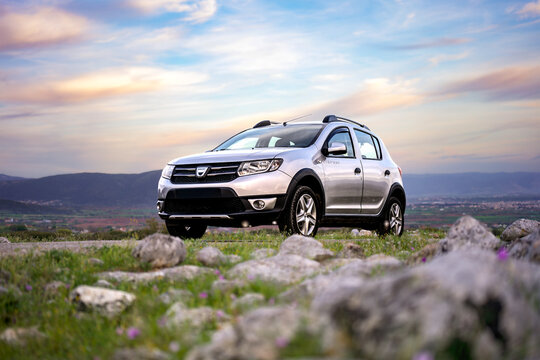 Low angle photography of a modern metallic silver crossover vehicle parked on rocky terrain emphasizing its strong front bumper design and readiness for adventurous outdoor countryside exploration.