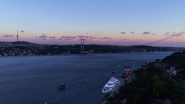 Aerial cityscape of Istanbul Bosphorus shoreline featuring waterfront estates, boats, deep blue sea, and green hills under clear sky