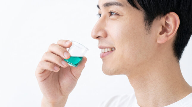 マウスウォッシュやうがい薬で口腔ケアをする若い男性