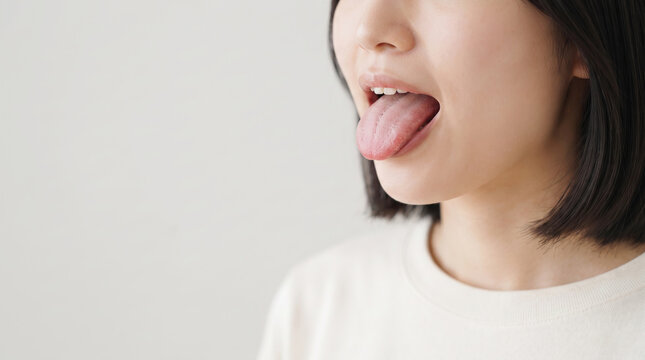 舌を出して健康状態や舌苔を確認する女性の口元