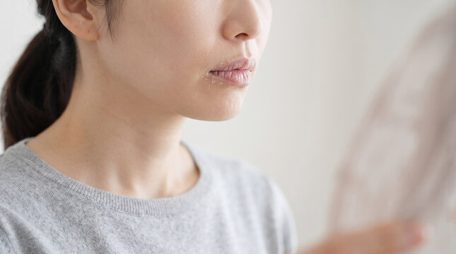 鏡を見ながら唇の乾燥や荒れに悩む女性のスキンケア
