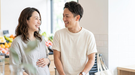Fototapeta premium スーパーで買い物をしながら笑顔で会話する妊婦と夫の夫婦