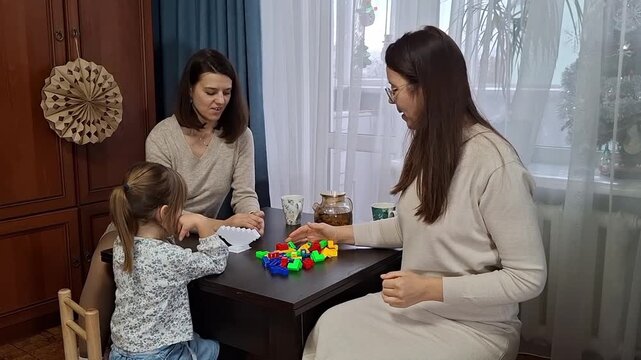 Children playing with colorful blocks at home during afternoon with family