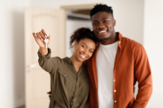 Smiling Young African American Couple Holding House Keys Together In New Apartment, Expressing Joy And Excitement For Home Ownership In Their Modern Living Space. Happy New Owners.