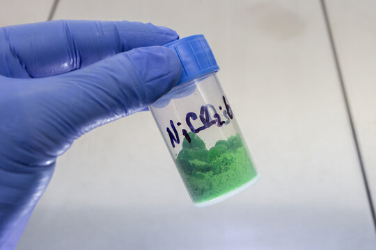 Clear plastic jar with green chemical salt, pure nickel chloride for chemical reactions.
