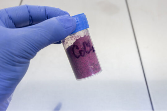 Cobalt chloride in a sealed plastic jar held by a scientist in a laboratory.